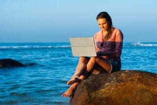 Frau mit Laptop am Meer