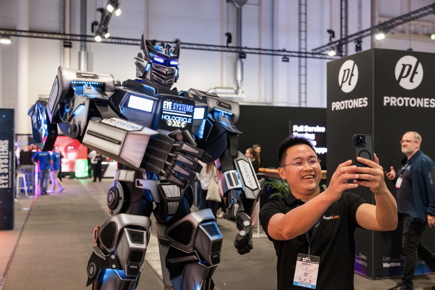 Roboter läuft über die Messe, während Besucher ein Foto mit ihm macht.